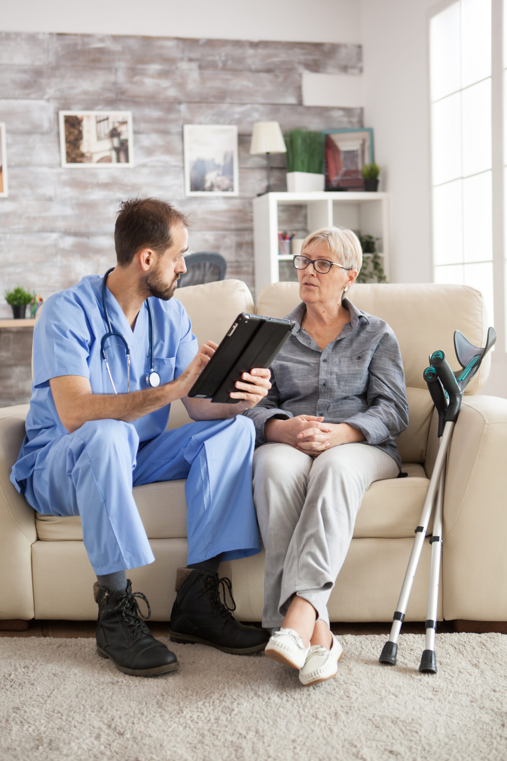 Elderly woman with crutches consulting a doctor about home care needs