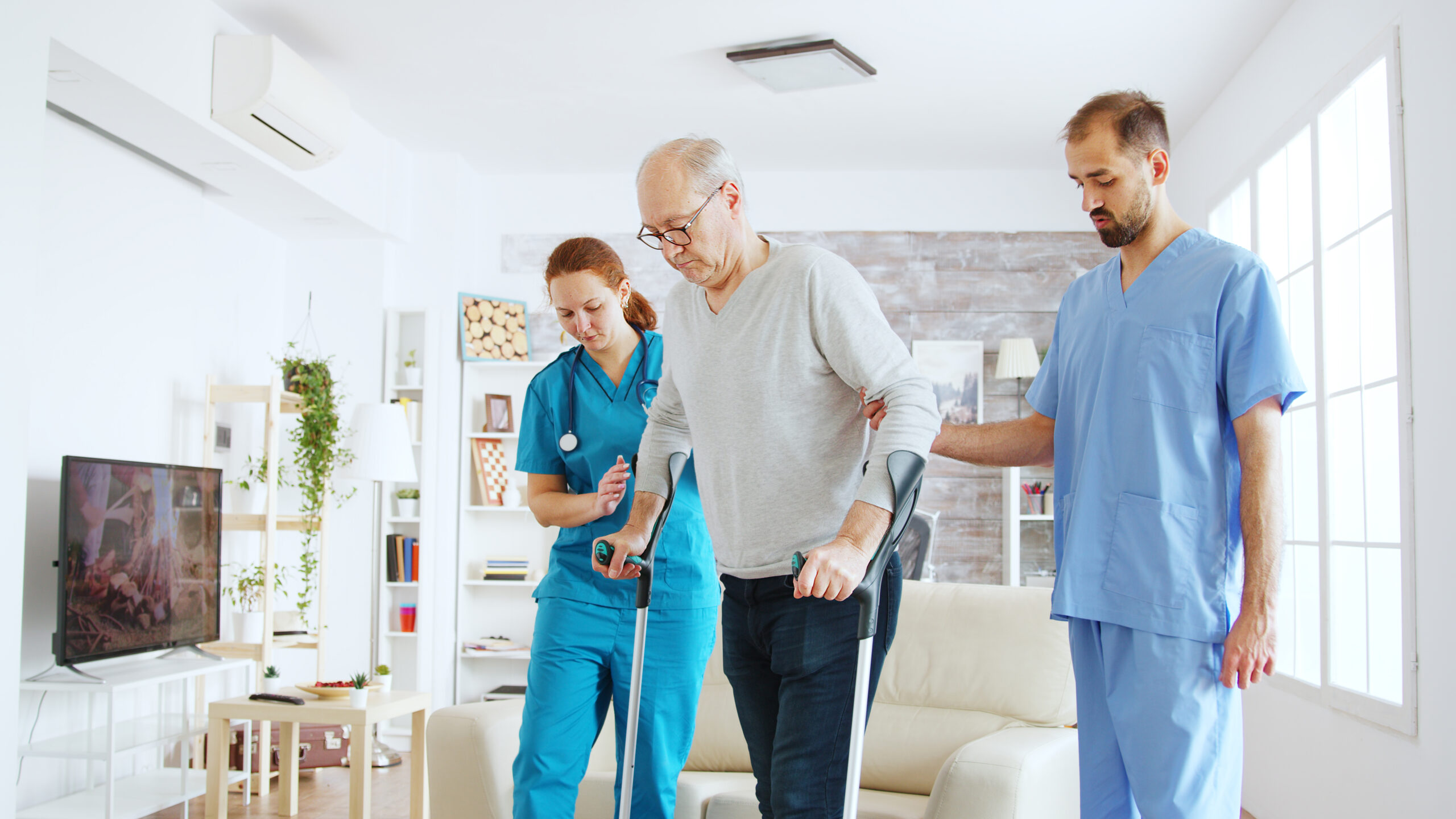 Nursing staff supporting an elderly patient with walking assistance